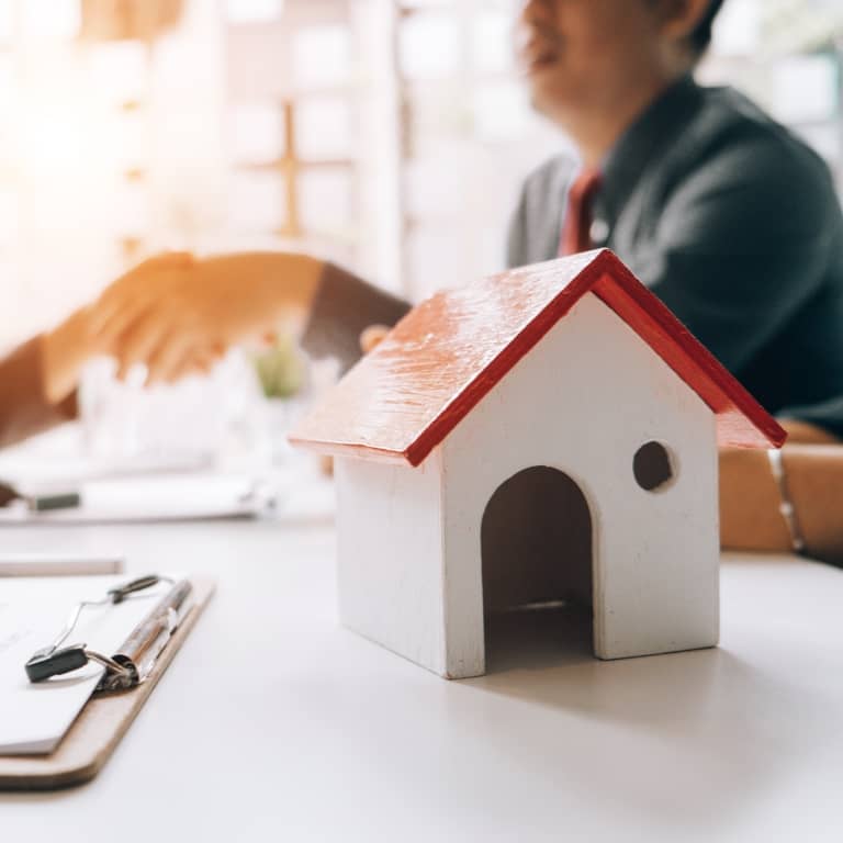 model house with people shaking hands in background